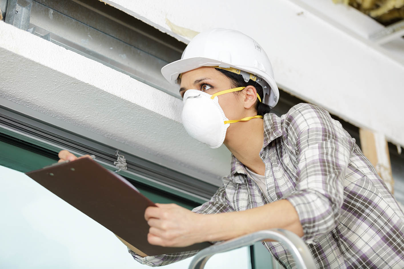 woman wearing mask and holding clipboard assessing worksite